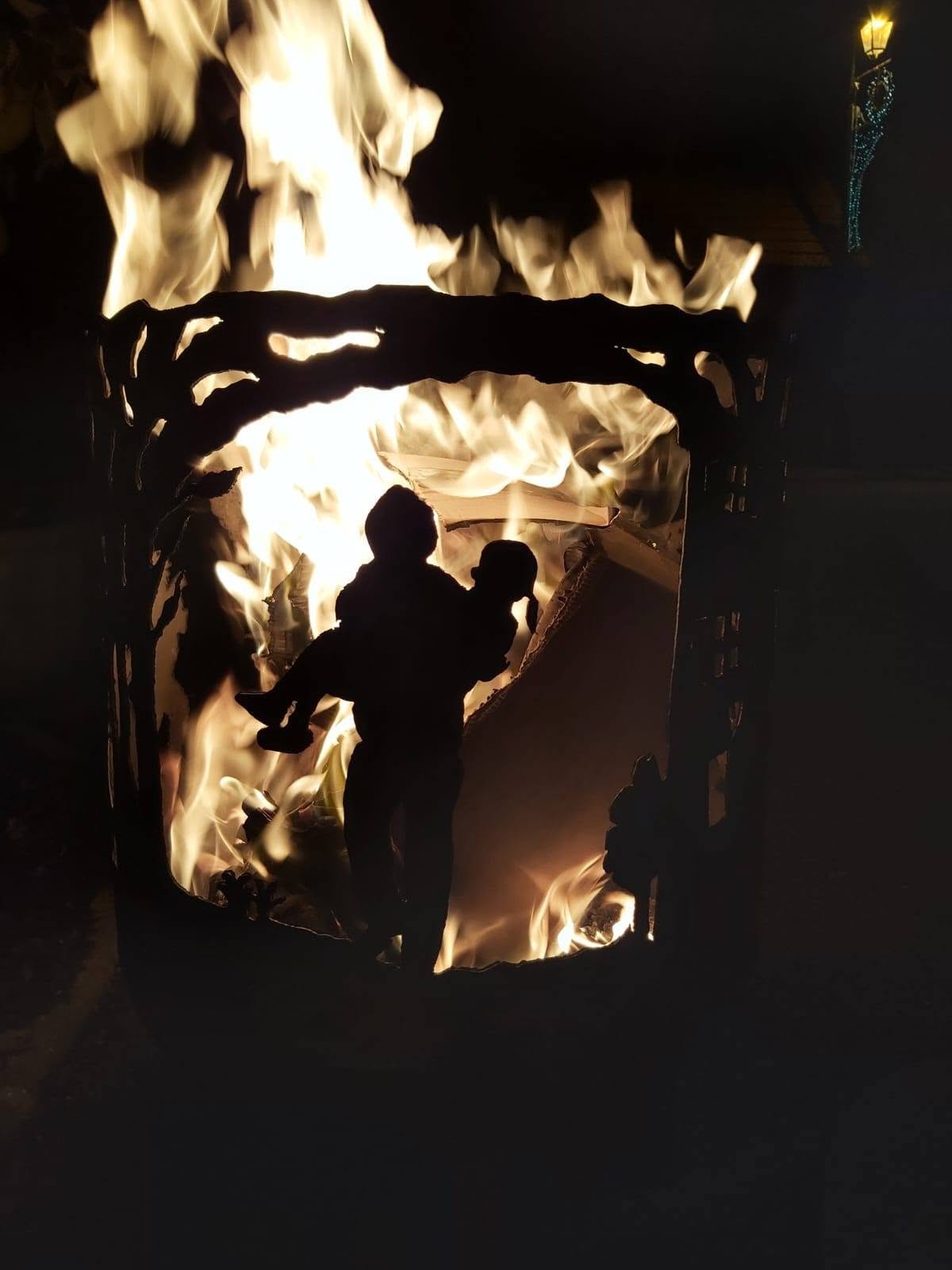 Brasero pompier allumé, silhouettes révélées par les flammes